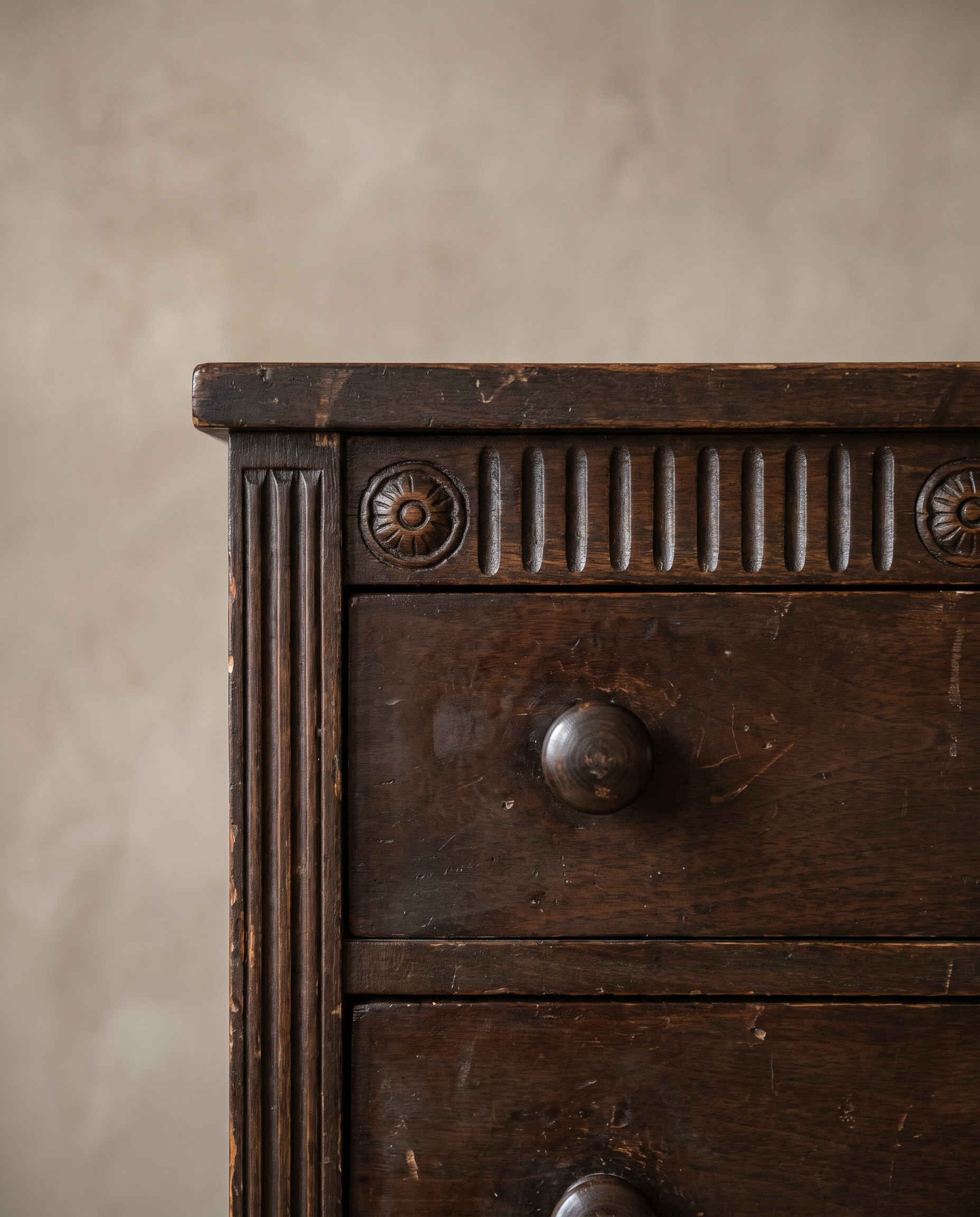 Close-up of the carved fluted frieze with rosettes and a turned wood drawer knob