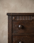 Close-up of the carved fluted frieze with rosettes and a turned wood drawer knob