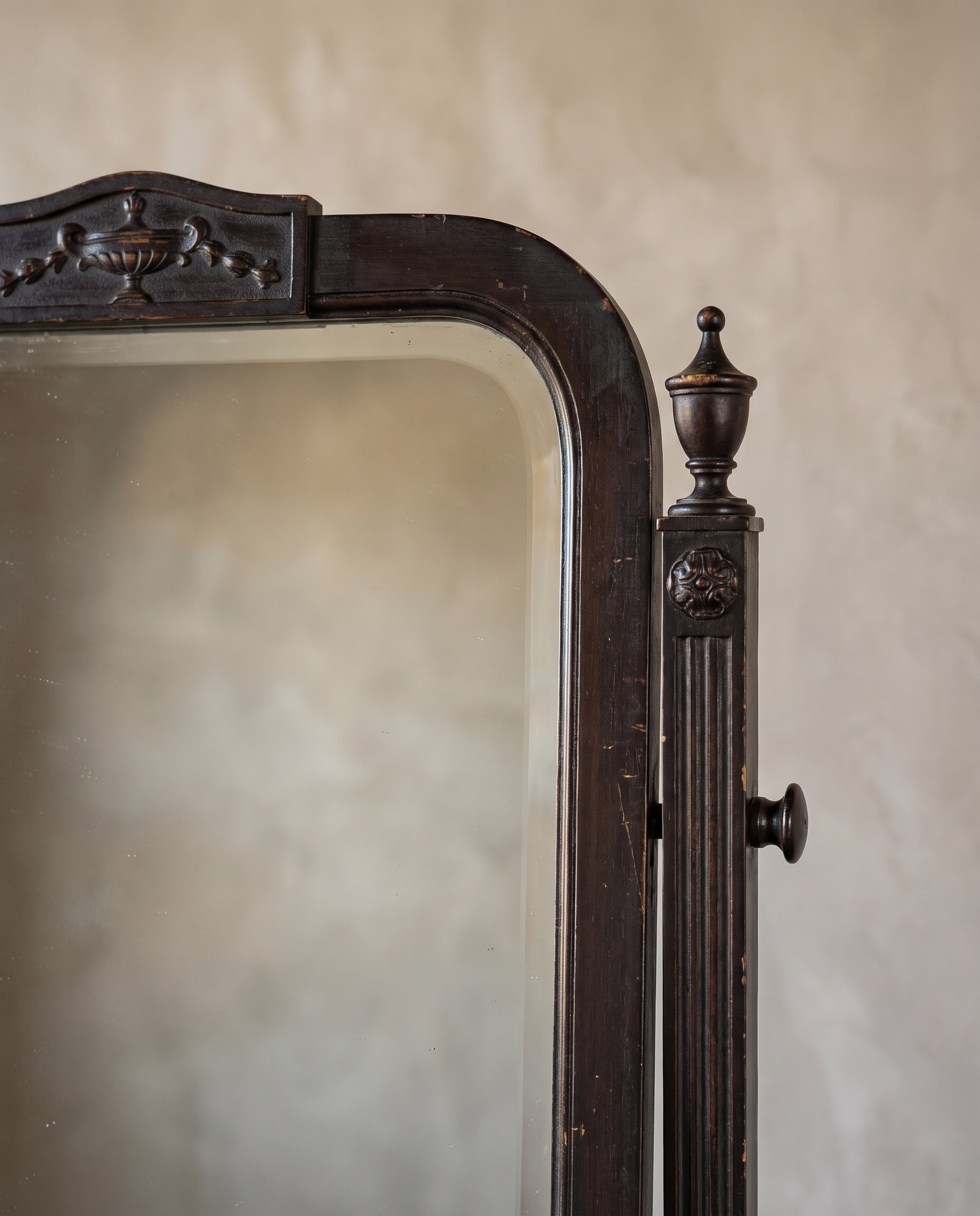 Close-up of the carved urn crest on the mirror frame and a fluted post with urn finial