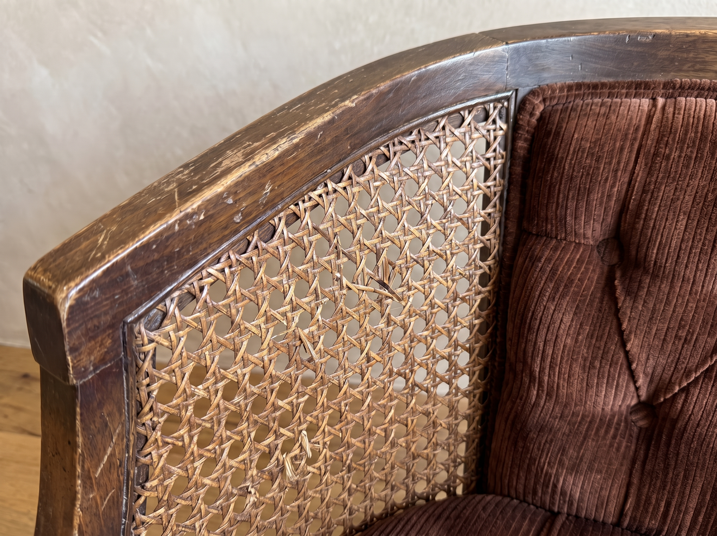 Close-up of the curved walnut arm, woven cane with natural wear, and tufted ribbed velvet