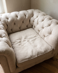 Looking down into the chair: diamond button tufting and the soft lived-in linen seat cushion