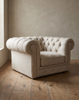 Side three-quarter view of the linen chesterfield chair showing its plain outer arm and low base