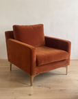Rust velvet armchair, three-quarter view from the left
