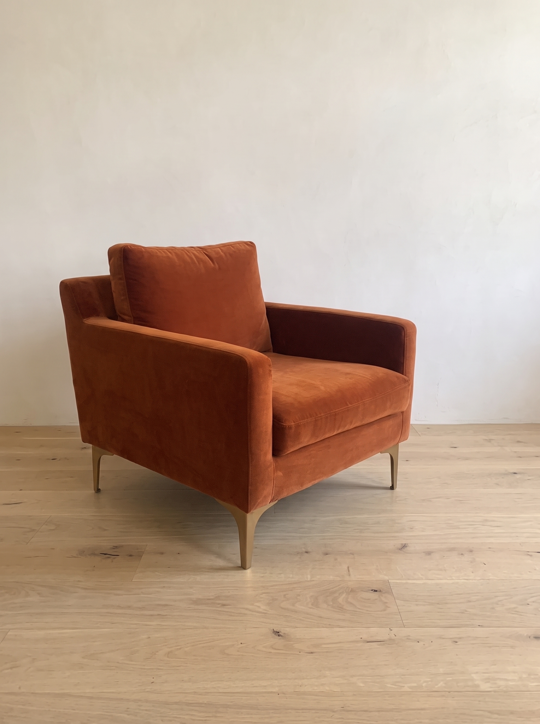 Rust velvet armchair, close three-quarter view showing track arm and brass legs