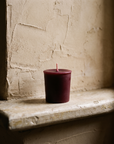 The votive on a worn stone ledge against rough limewash plaster