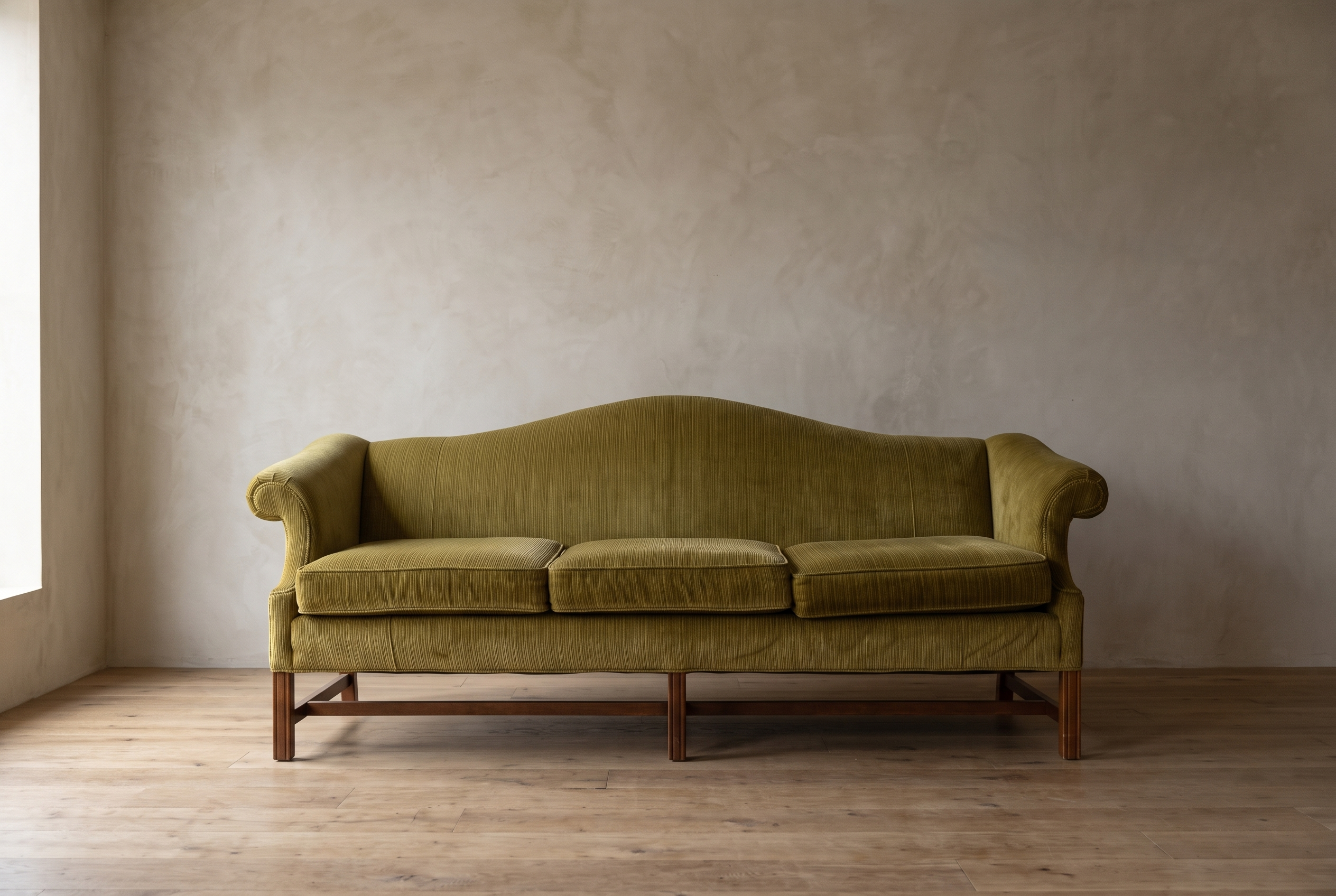 Straight-on front view of the chartreuse camelback sofa showing six mahogany legs and stretchers