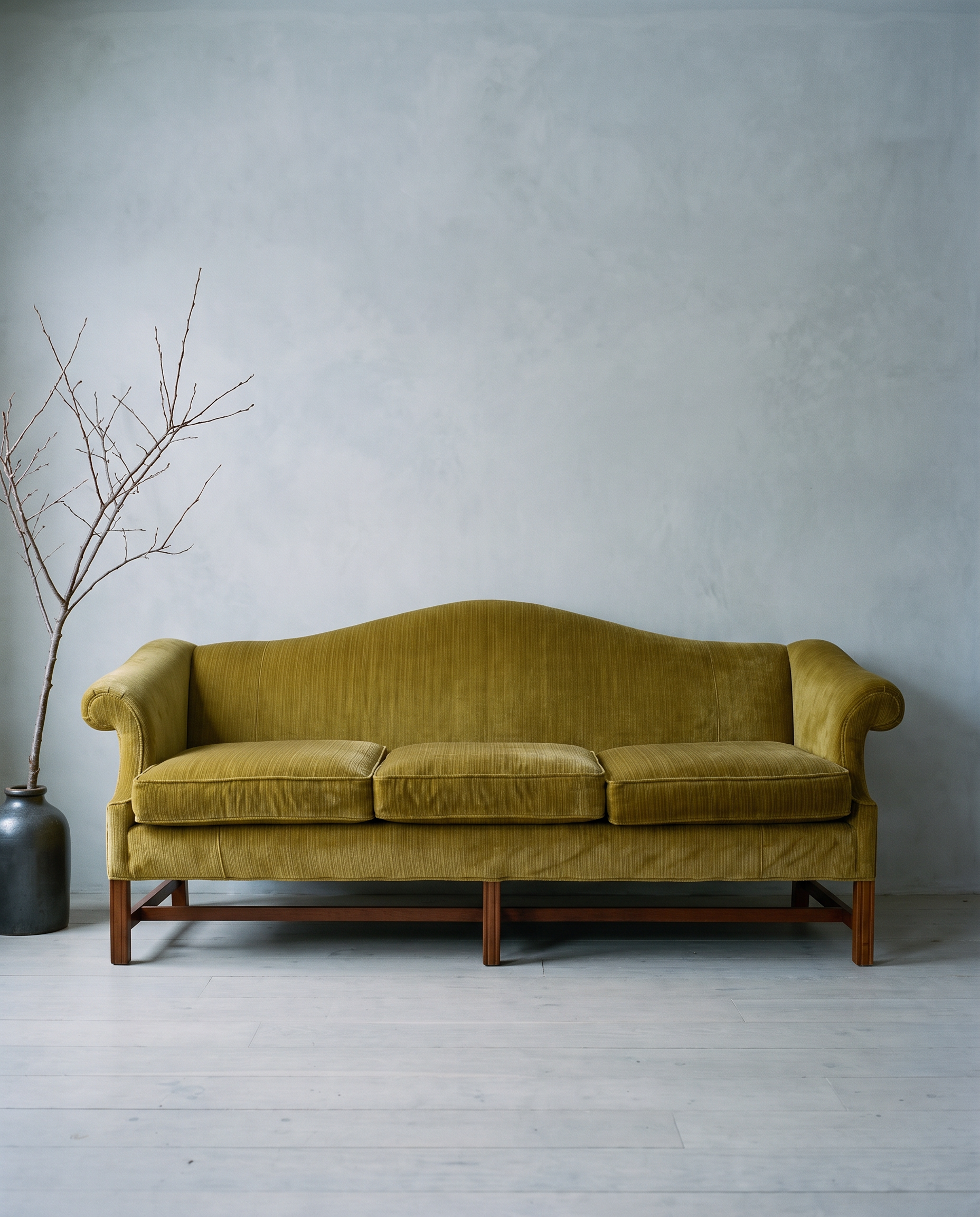 Chartreuse camelback sofa in a cool grey winter room with a bare branch