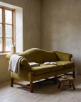 Chartreuse camelback sofa in a morning reading corner with a linen throw and open book