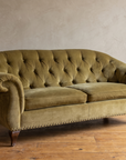 Three-quarter view of the olive velvet tufted sofa with walnut scroll legs