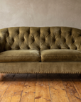 Straight-on front view of the olive velvet tufted sofa showing scroll arms and nailhead trim