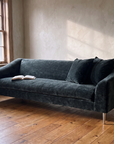 Tess sofa in morning window light with an open book on the cushion and a bare branch in a stoneware jug