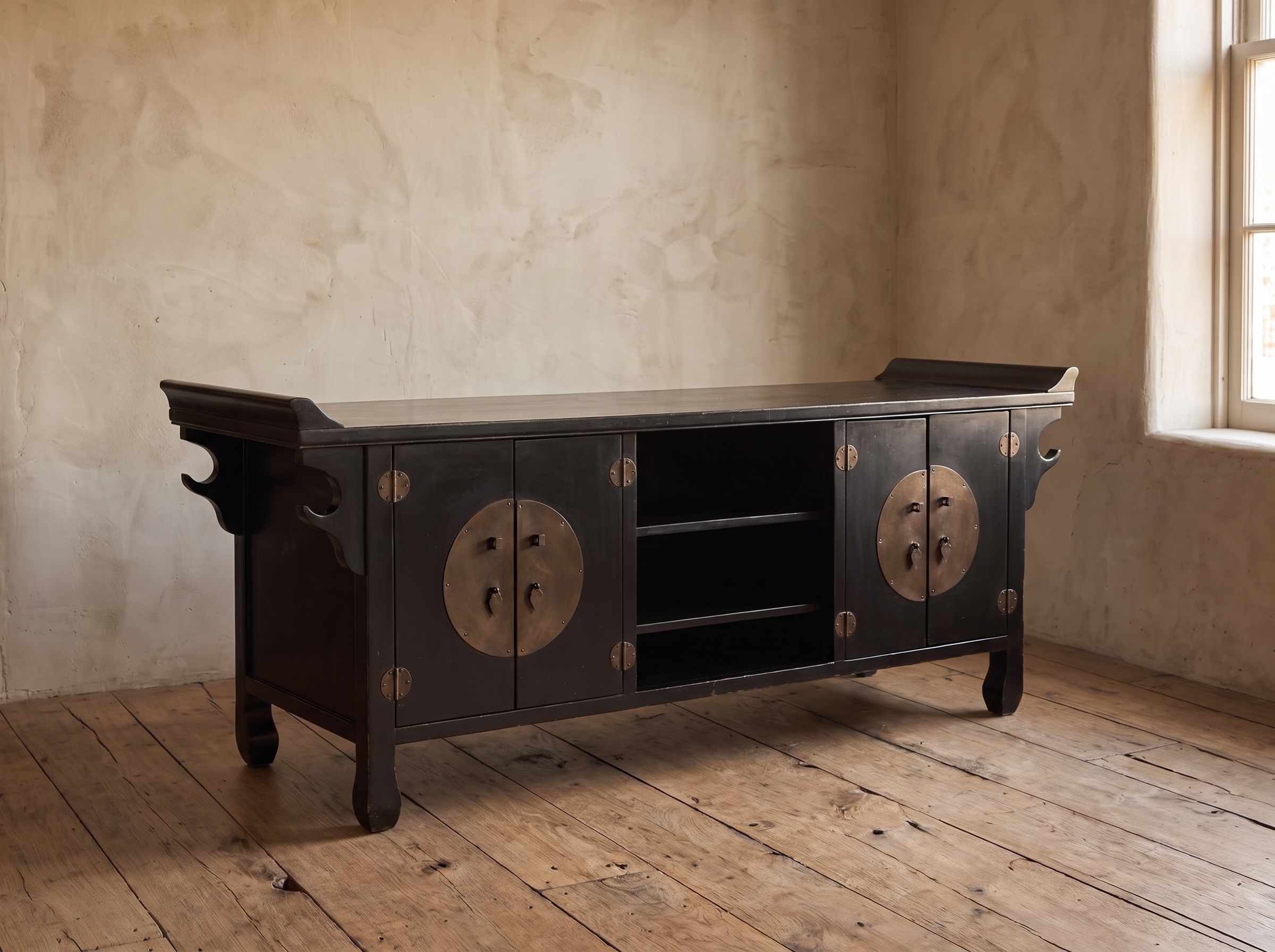 Black lacquer Chinese TV console with round bronze door plates in a plaster room with reclaimed wood floor