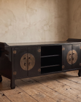 Black lacquer Chinese TV console with round bronze door plates in a plaster room with reclaimed wood floor