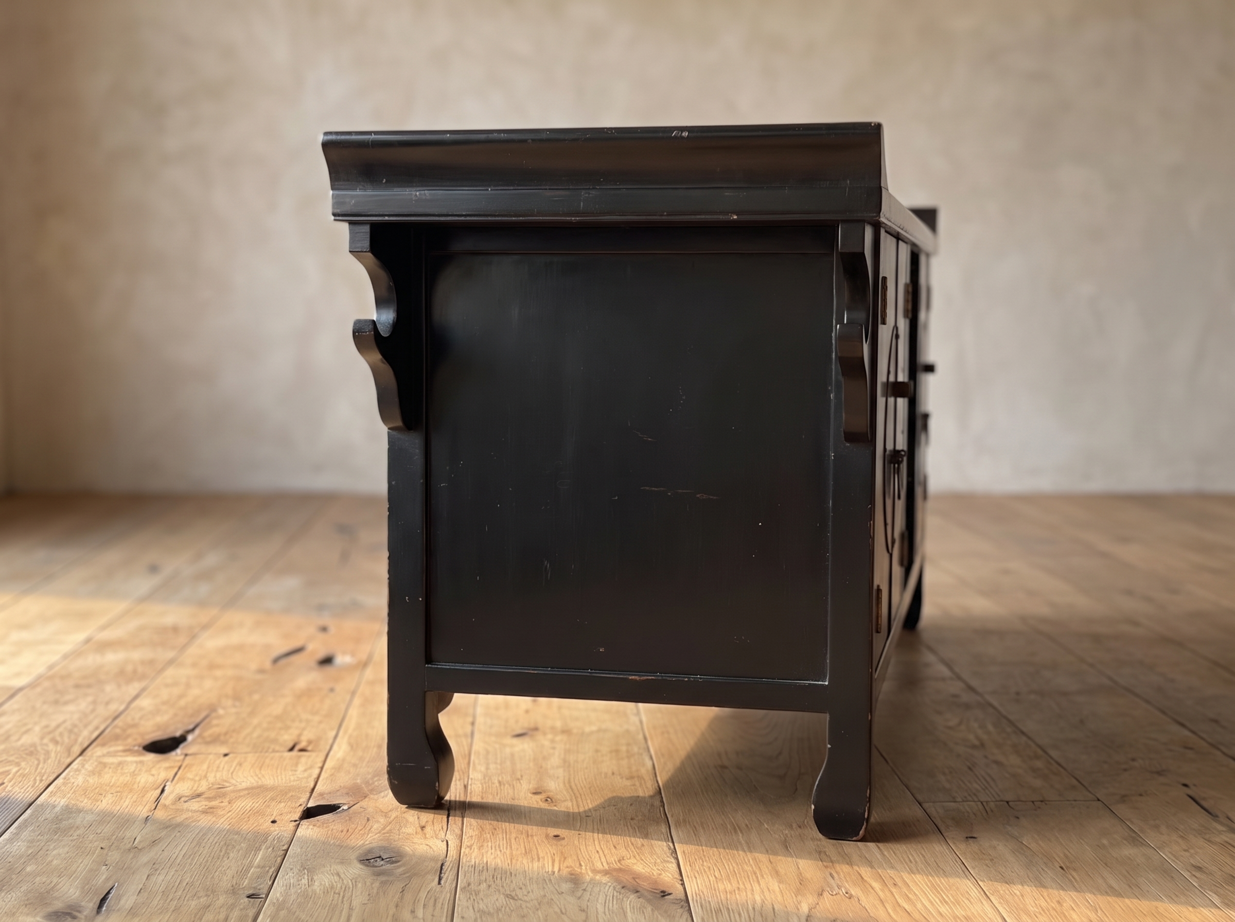 Side profile of the black lacquer console showing scroll brackets and hoof feet