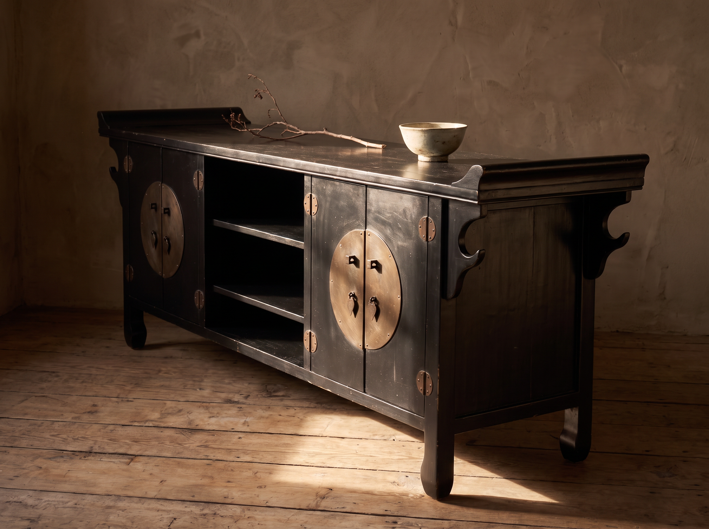 Black lacquer console in warm raking afternoon light with a pale bowl and dried branch on top