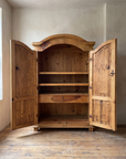 Armoire with both doors open showing pine shelves and a small keyed drawer