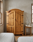 The armoire in a quiet bedroom with morning window light and a small nightstand