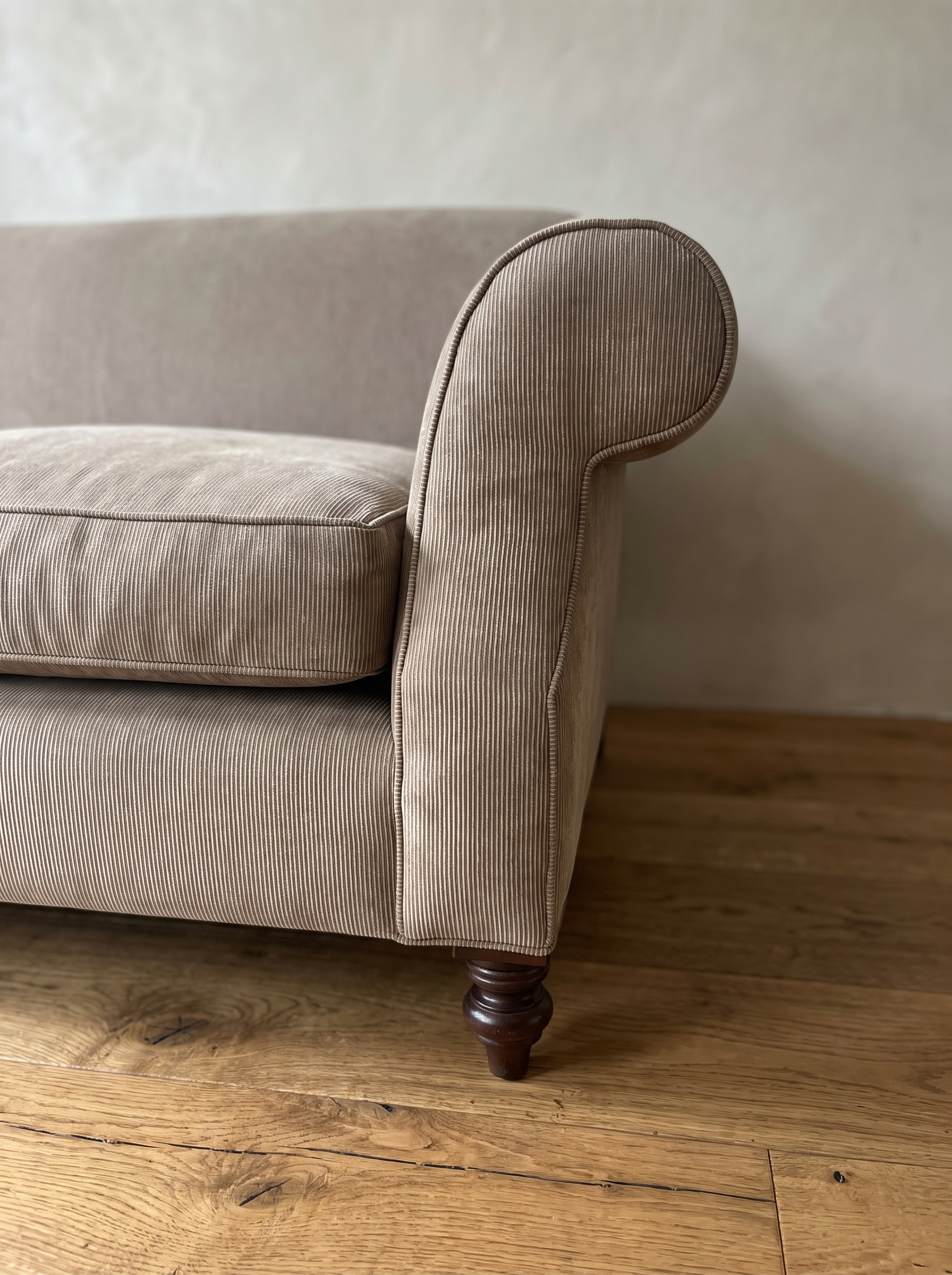 Close-up of the rolled scroll arm with self-welt piping and fine pinstripe cotton ticking