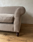 Close-up of the rolled scroll arm with self-welt piping and fine pinstripe cotton ticking