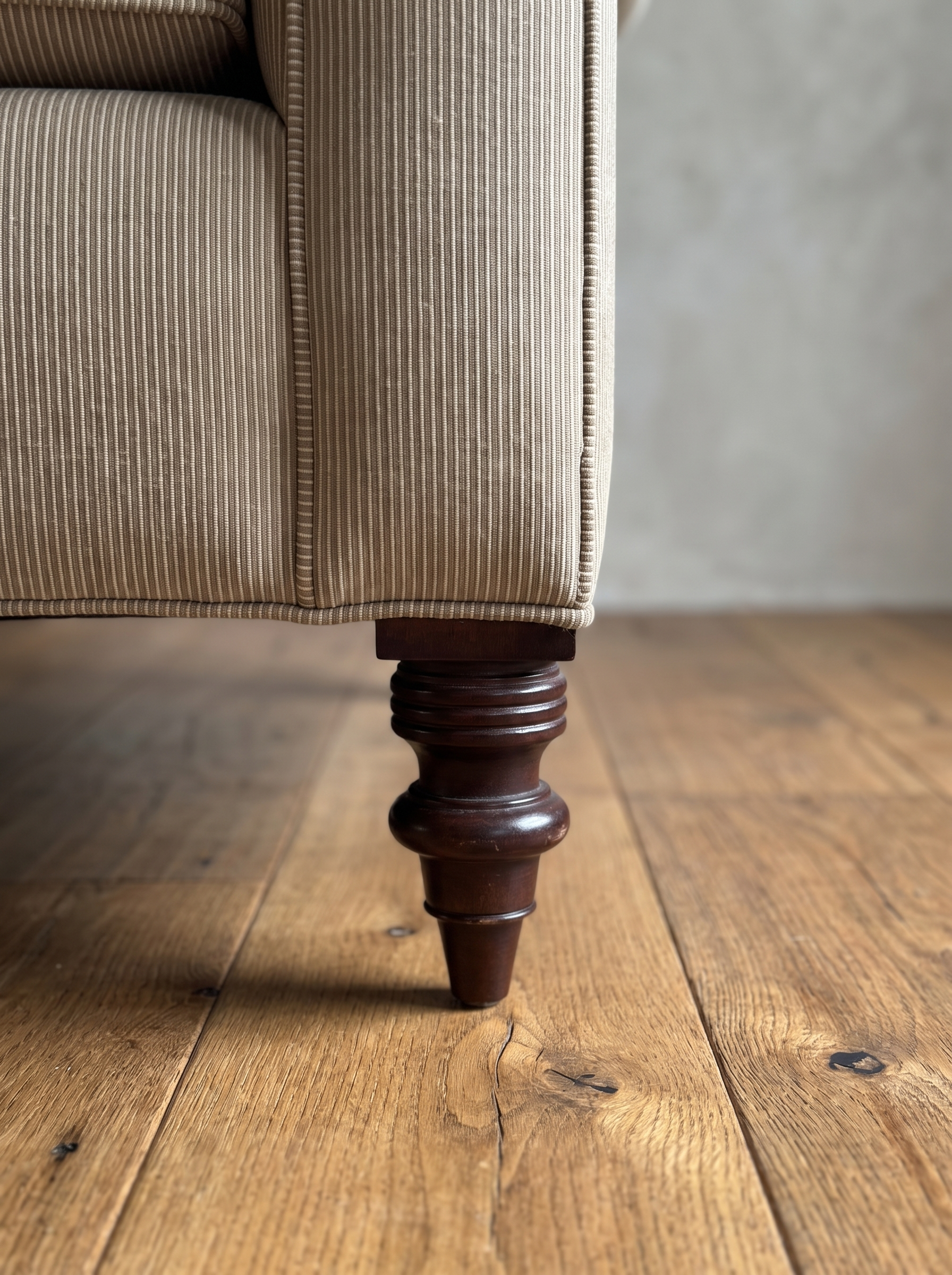 Close-up of the turned dark mahogany leg and welted corner