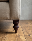 Close-up of the turned dark mahogany leg and welted corner