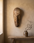 Liberian carved wood mask on a plaster wall