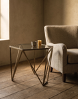 Facets brass side table beside a linen armchair