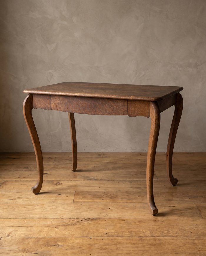 Antique tiger oak writing desk with cabriole scroll legs, three-quarter view in a plaster room with a reclaimed wood floor
