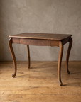 Antique tiger oak writing desk with cabriole scroll legs, three-quarter view in a plaster room with a reclaimed wood floor