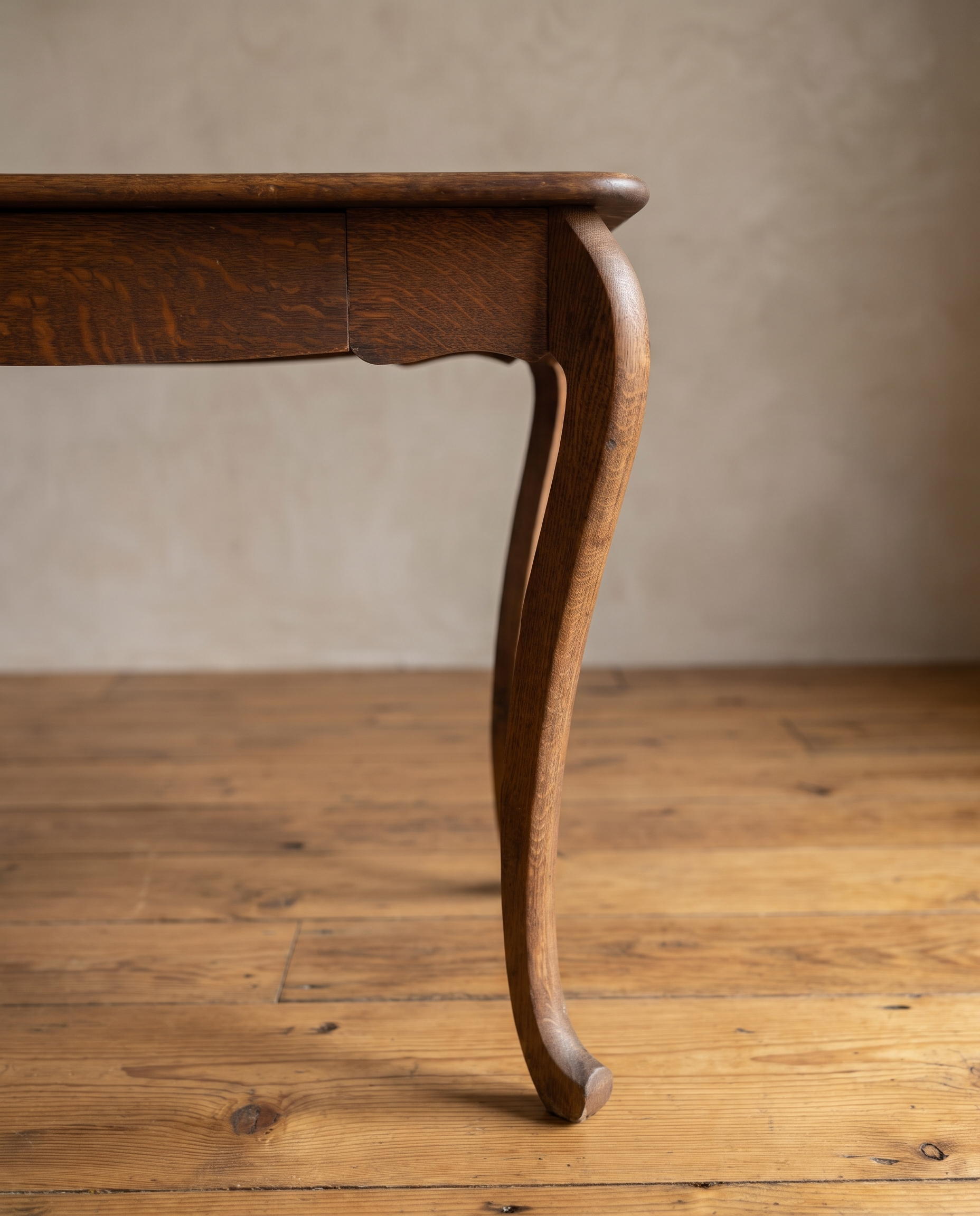 Close-up of a cabriole leg ending in a small scroll toe, with the scalloped apron above