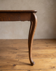 Close-up of a cabriole leg ending in a small scroll toe, with the scalloped apron above