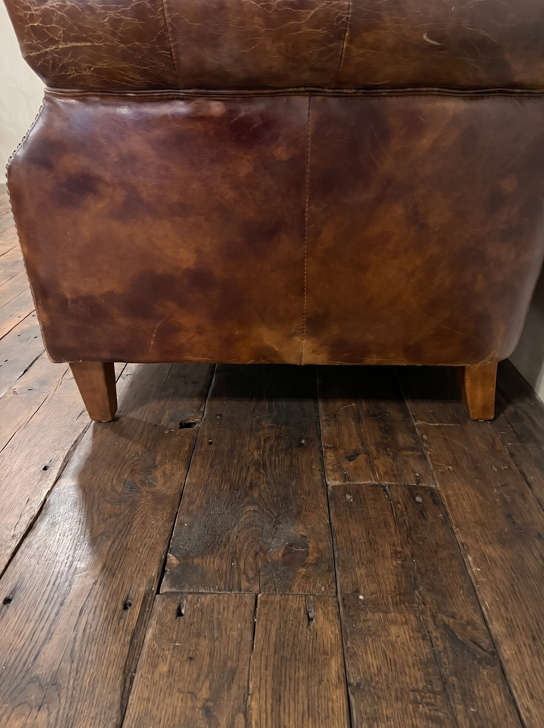 Detail of the smooth outside back panel, mottled tobacco leather patina, seams and tapered legs