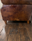 Detail of the smooth outside back panel, mottled tobacco leather patina, seams and tapered legs