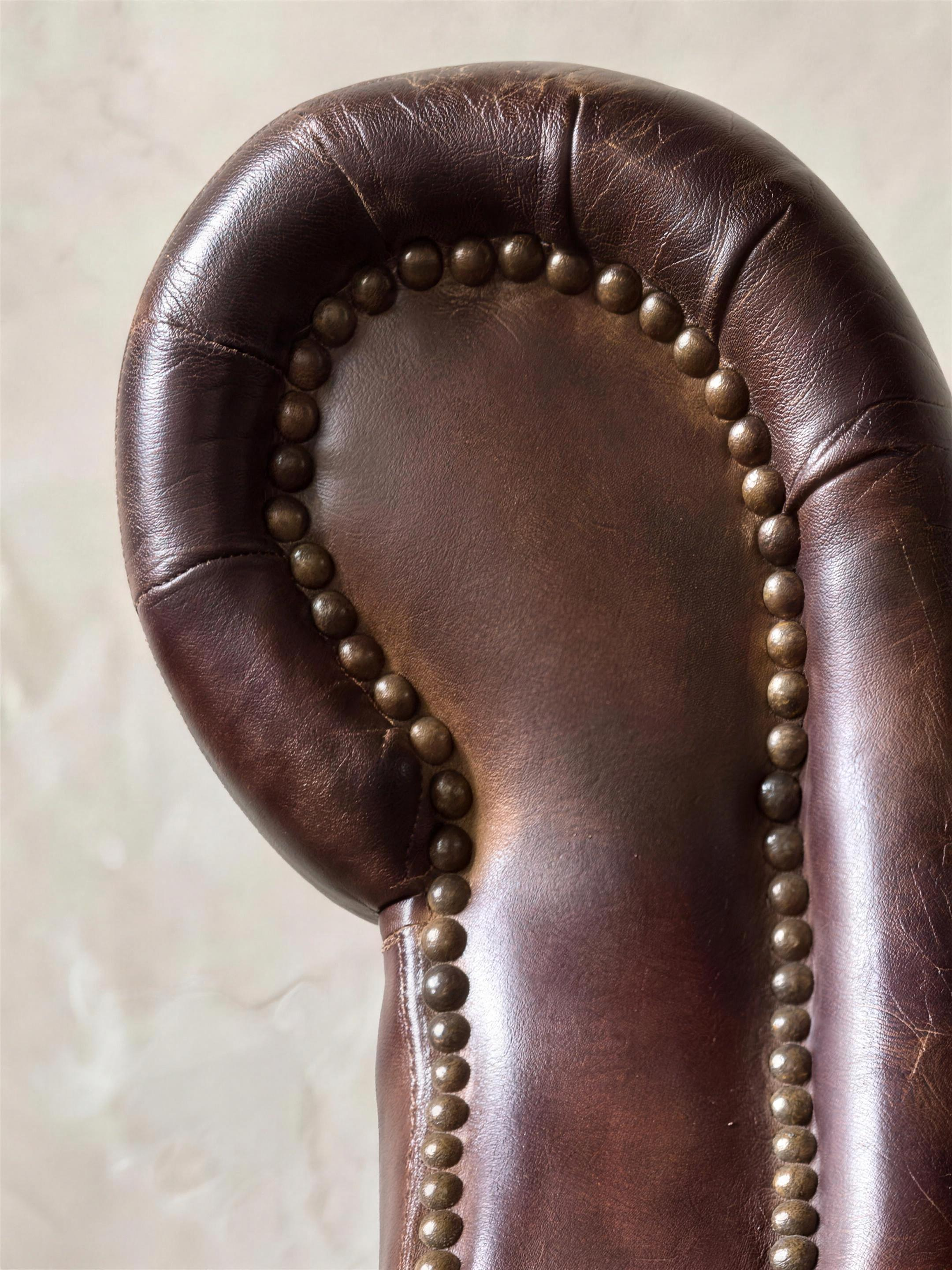 Close-up of the scroll arm curl traced in antique brass nailheads