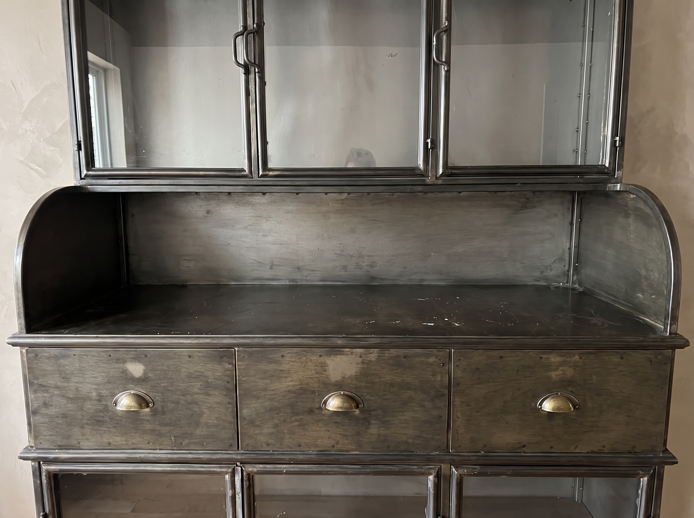 The open steel counter with rounded side galleries between the upper glass doors and the drawers