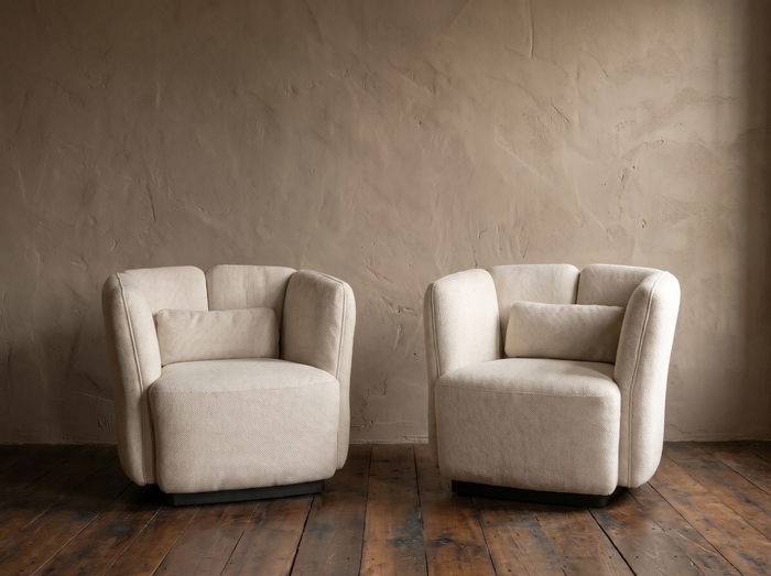 Pair of white textile Ford armchairs by Living Couture against a warm taupe plaster wall on dark reclaimed wood floor