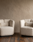 Pair of white textile Ford armchairs by Living Couture against a warm taupe plaster wall on dark reclaimed wood floor