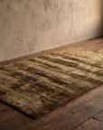 Ralph Lauren olive and umber abstract silken pile rug on dark reclaimed wood floor in a taupe plaster room