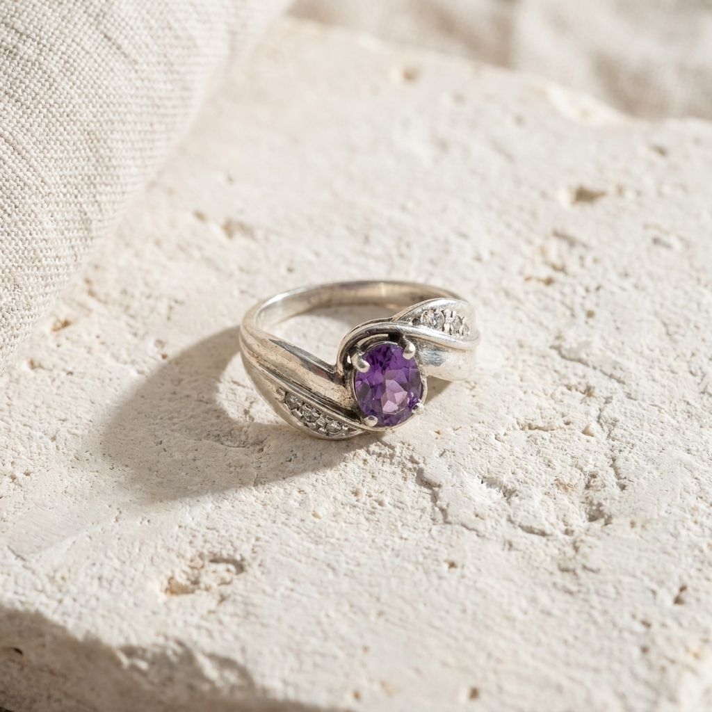 Sterling silver ring with a round amethyst and crossing ribbons set with small clear stones