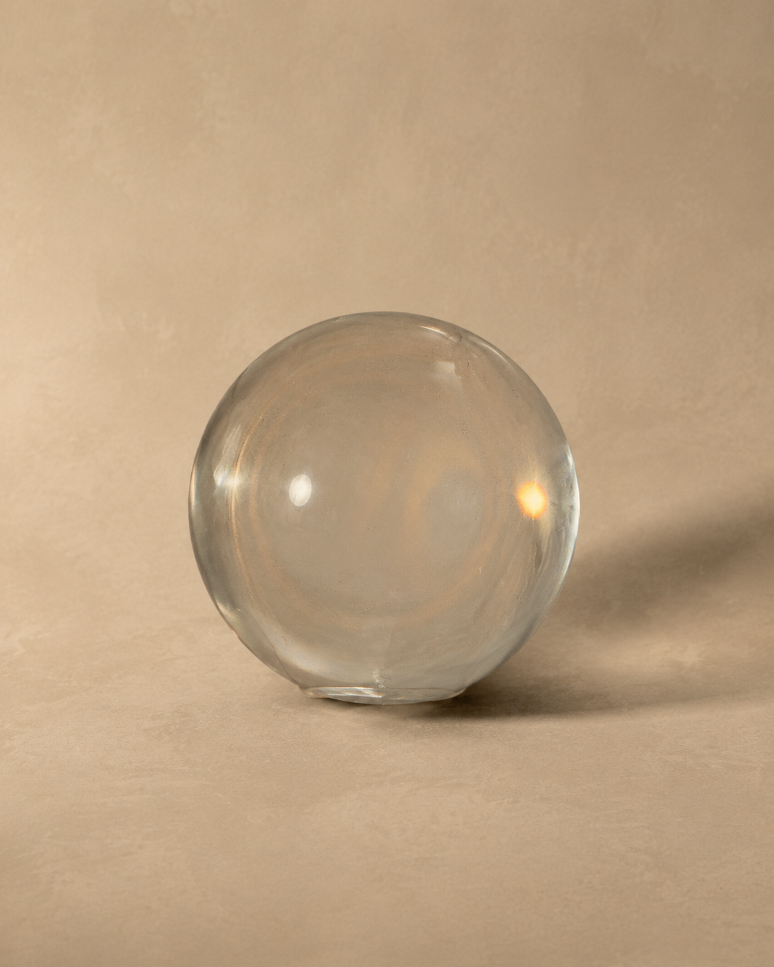 Large Glass Marble, clear solid glass sphere catching light on a warm neutral surface