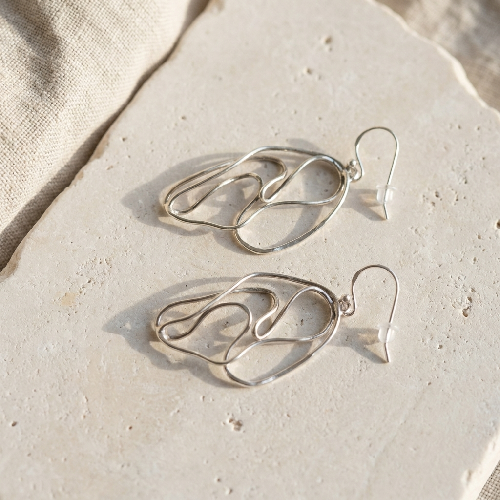 Large open loop hammered sterling silver earrings laid flat on pale stone
