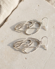 Large open loop hammered sterling silver earrings laid flat on pale stone