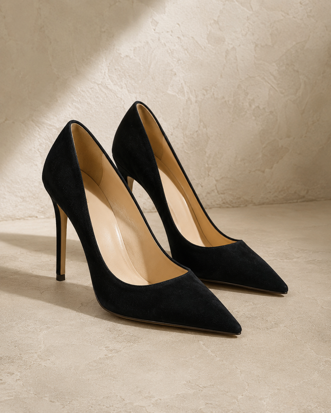 Christian Louboutin Black Suede Pumps, pointed-toe stilettos in black suede on a plaster backdrop